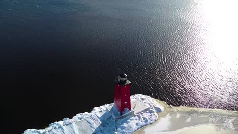 manistique michigan's very bright red light house on a sunny winter day