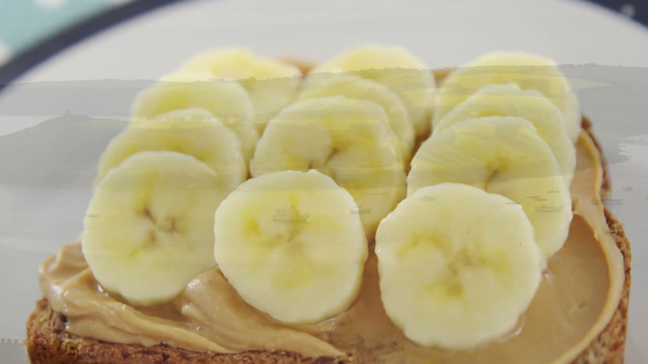Banana slices on peanut butter toast over scenic landscape animation