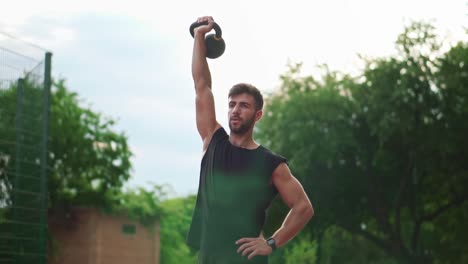 A-Portrait-Of-A-Man-In-Black-Sportswear-Trains-With-Weight-Bob-Outdoors-Close-To-The-Stadium-On-The-Racetrack-In-Slowmo