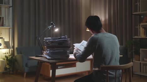 압력의 뒷면: 아시아 남자가 집에서 문서와 함께 열심히 일하면서 종이를 버립니다.