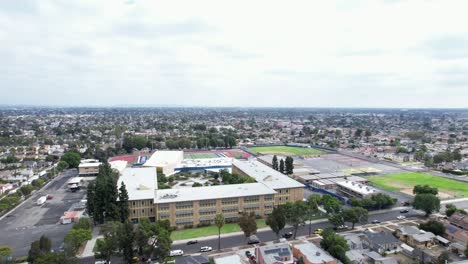 wide orbiting aerial view of crenshaw high school campus, south los angeles district, california