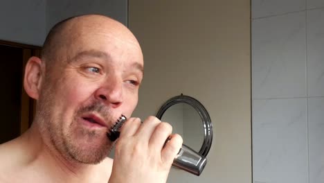 male shaves with an electric razor