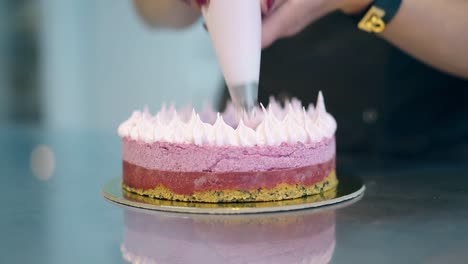 confectioner decorates three-layer round cake with cream