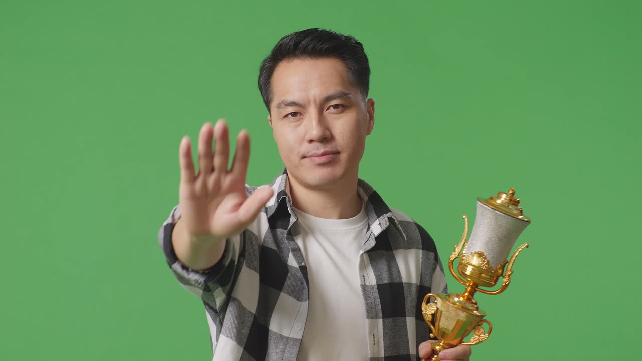승인을 거부하는 손짓으로 트로피를 들고 있는 남자