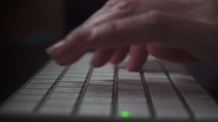 En hånd skriver på et tastatur, mens der arbejdes på en Mac-computer.