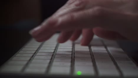 A-hand-writing-on-a-keyboard-while-working-in-a-Mac-computer