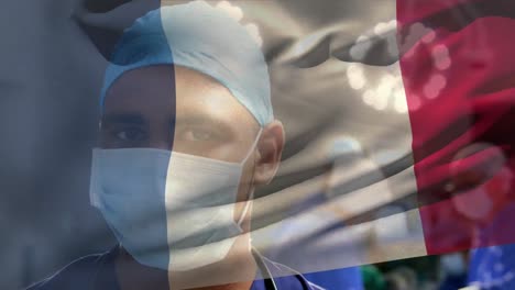 Animation-of-flag-of-france-over-biracial-male-surgeon-with-face-mask