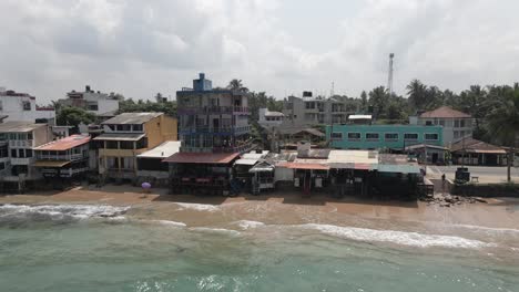 Aerial-view:-Ramshackle-waterfront-buildings-on-Sri-Lanka-coast-sand