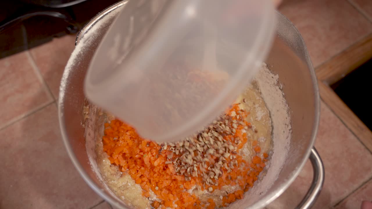 mescolando la pastella con noci e carote per torta