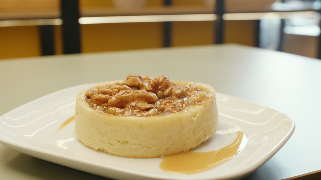 Panning shot of a cheesecake garnished with whole walnuts on top, highlighting its creamy texture and crunch