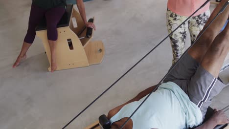 focused diverse senior people exercising on devices with female coach in slow motion