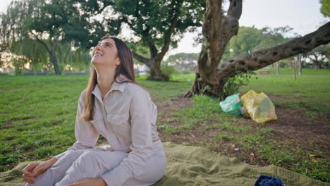 woman enjoy park serenity sitting on grass basking at sunlight. smiling lady