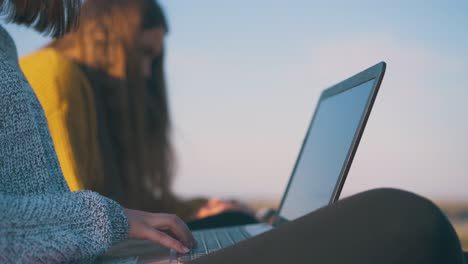 woman-with-laptop-near-friend-at-campsite-in-autumn-evening