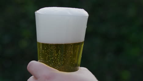 slow motion video raising a filled glass of beer with blurred background