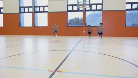 playing basketball in school gym, three boys running and dribbling ball