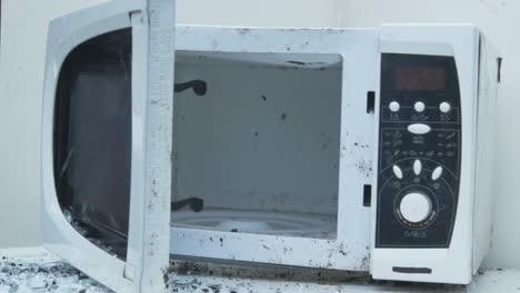 slow motion of smashing old microwave oven with a metal hummer