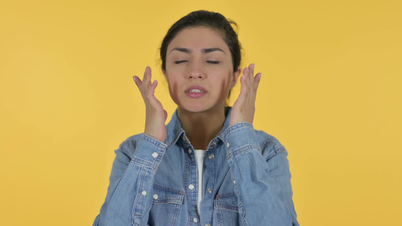 두통을 고 있는 젊은 인도 여성, 노란색 배경