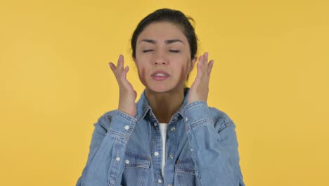 young indian woman having headache, yellow background