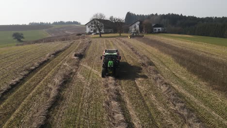 combine harvester tractor collecting hay crop on bavarian hemp field