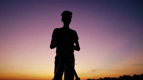 silhouette of a photographer with camera and tripod at sunset