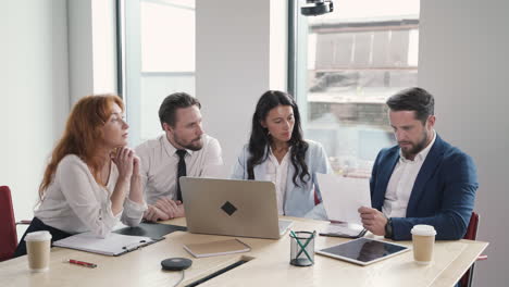 business meeting between two women and two businessmen. one of the parts hands over a contract to sign and the other part refuses to do it.