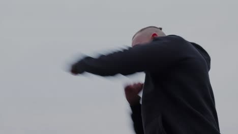 hero shot of a young man shadowboxing against a gray sky