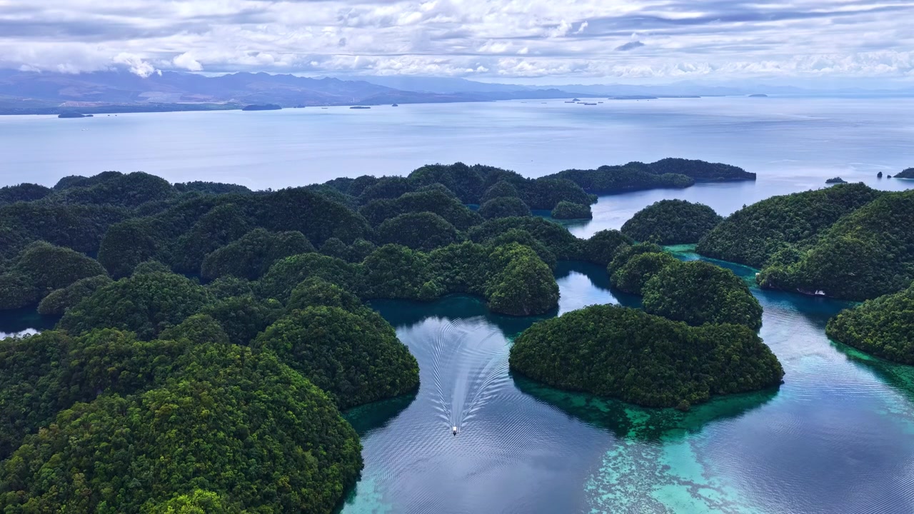 Spettacolare ripresa aerea grandangolare con drone su Sohoton Cove nelle Filippine. Mostra barche che navigano attraverso lagune turchesi cristalline, circondate da lussureggianti isole carsiche calcaree verdi e nebbia mattutina.