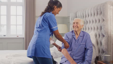 Hombre-Mayor-En-Casa-En-La-Cama-Con-La-Presión-Arterial-Tomada-Por-Una-Trabajadora-De-Cuidado-En-Uniforme