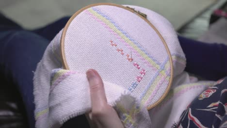 empujón lento en la toma de una mujer coser patrones cruzados en el material como un regalo