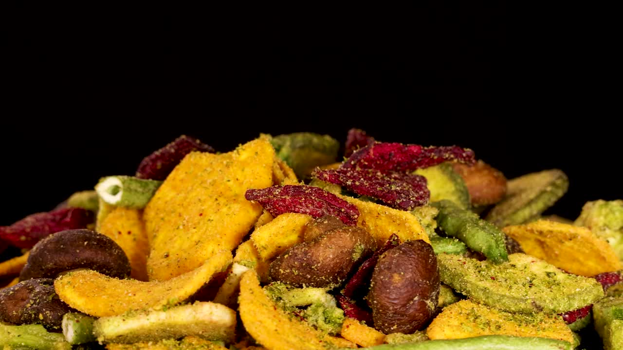 Colorful dried vegetable chips rotate under studio lighting, highlighting texture and crunchy detail