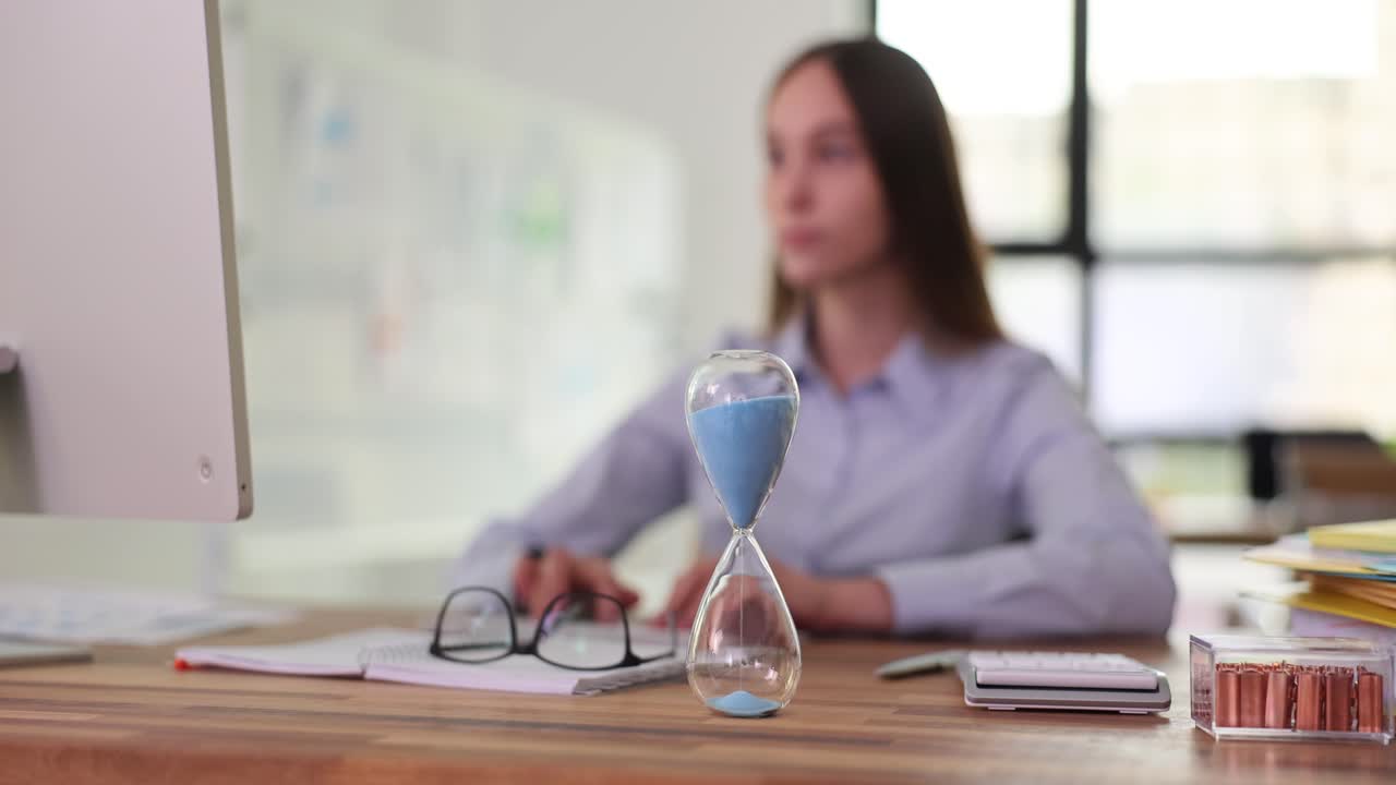Woman working at desk with hourglass