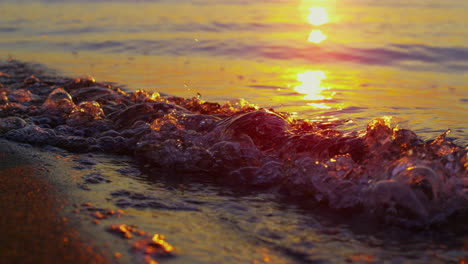 las olas del mar de cerca rompiendo la orilla de la tarde en cámara lenta. la luz del sol reflejada