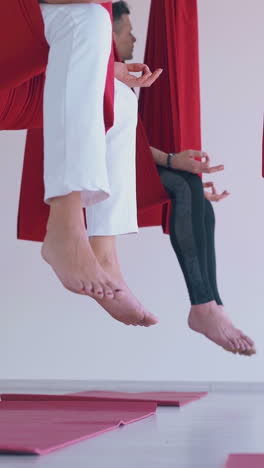 slim women legs in leggings and bare feet hang down from oriental fly yoga hammocks and swing close view