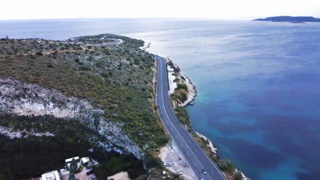 Toma-Aérea-Sobre-La-Costa-Y-La-Carretera-Junto-Al-Mar-En-La-Zona-De-Vouliagmeni-En-Atenas-|-4k