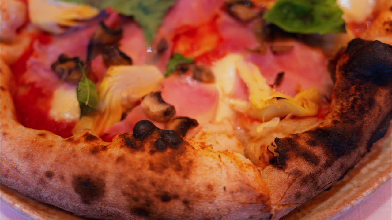 Close up of pizza with artichoke, ham, mushrooms and basil
