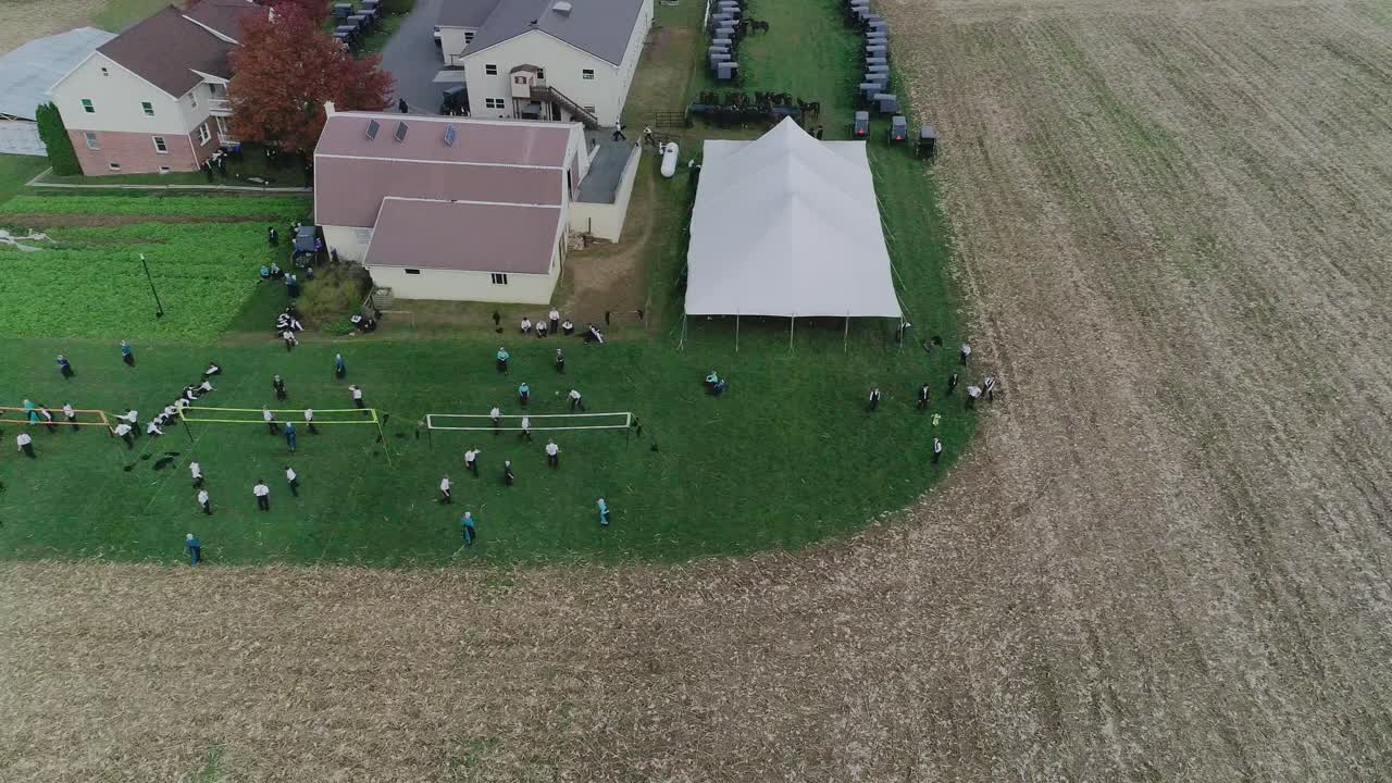 vista de ariel de una boda amish en un día de otoño con buggies, un amish jugando voleibol visto por un dron
