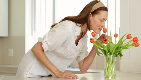 Woman-smelling-her-vase-of-tulips-and-smiling-at-camera