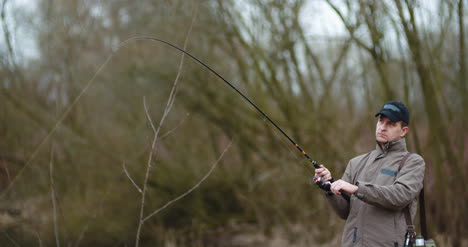 Man-Fishing-At-Lakeshore-In-Forest-17