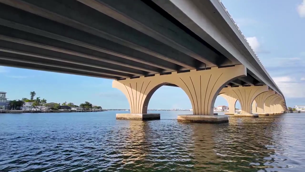 En fredelig bådtur nærmer sig Pinellas Bayway Bridge under blå himmel og drivende skyer på en smuk sommerdag langs Floridas Golfkyst