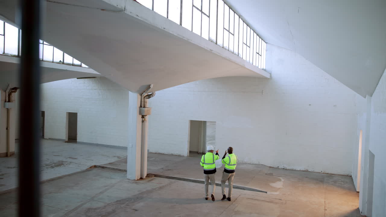 Construction workers inspecting warehouse with blueprint