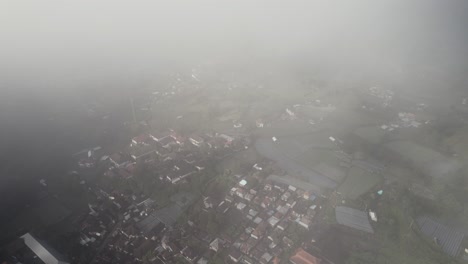 el avión no tripulado vuela sobre el paisaje brumoso revelando el pequeño pueblo de kintamani en la isla de bali, indonesia.