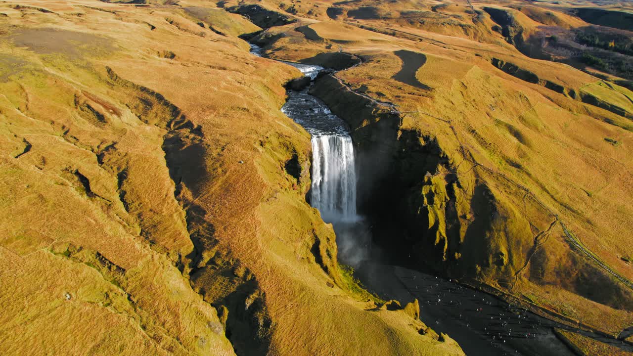 vista panorámica de la cascada islandesa skogafoss rodeada de follaje de musgo amarillo durante la puesta de sol