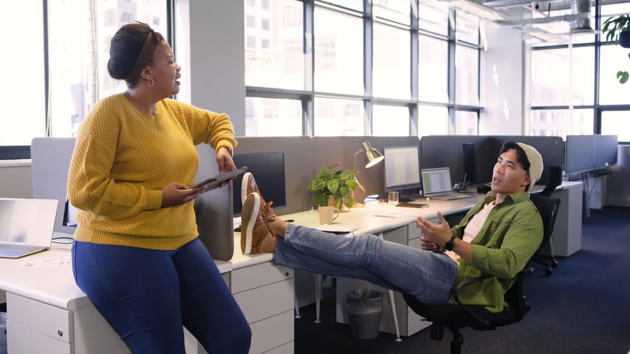 Colegas de trabalho diversos se inclinando sobre a mesa do escritório enquanto discutem os detalhes do projeto com tablet e telefone
