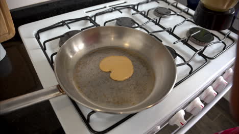 movimiento lento de un hombre cocinando preparando un panqueque en forma de corazón para su esposa novia en una sartén de acero inoxidable para el día de san valentín
