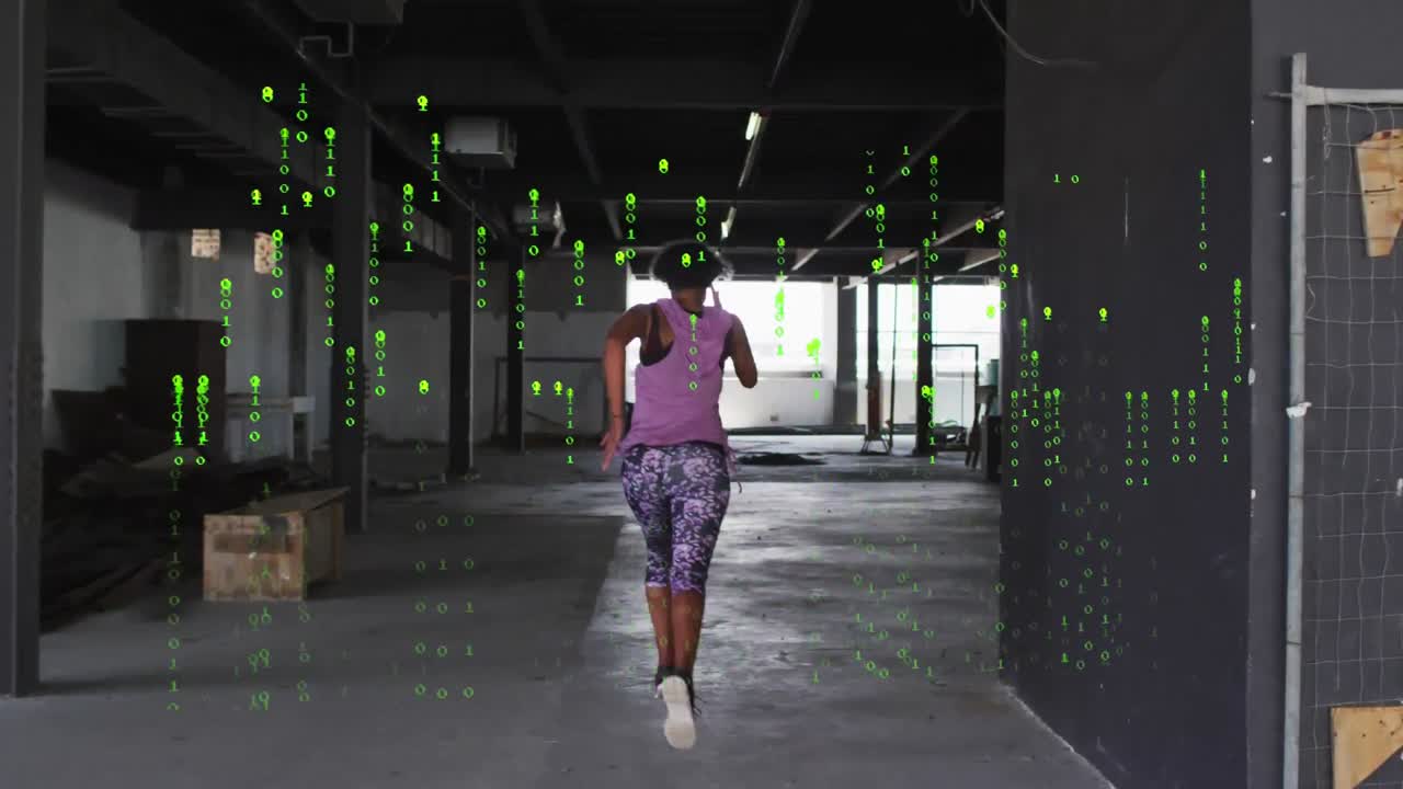 Animation of falling binary codes, rear view of biracial woman running in empty warehouse