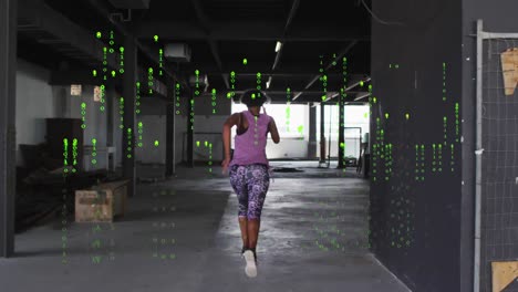 Animation-of-falling-binary-codes,-rear-view-of-biracial-woman-running-in-empty-warehouse