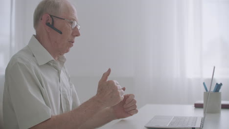 aged-man-is-communicating-with-friends-or-colleagues-by-video-call-talking-looking-at-screen-of-laptop-online-communication