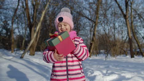 Fröhliches-Lächelndes-Mädchen-Blickt-Mit-Weihnachtsgeschenk-Geschenkbox-In-Die-Kamera-Im-Verschneiten-Winterpark