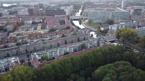 Glittering-canal-seen-in-the-middle-of-a-suburb-in-the-magnificent-Amsterdam-at-sunset,-aerial-view