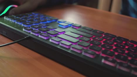 joven jugador juega un videojuego utiliza el teclado iluminado del juego 04